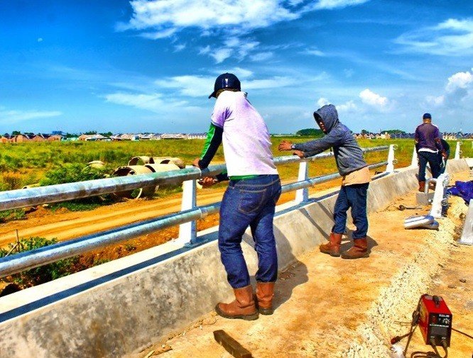 Pekerja memasang railing pipe di tepi jembatan